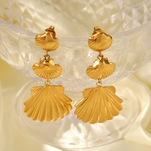 Close-up of 18K gold plated stainless steel triple shell earrings on a glass bowl edge
