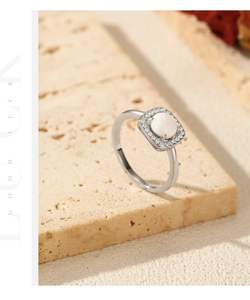Detailed macro shot of an oval opal halo ring resting on textured beige stone props