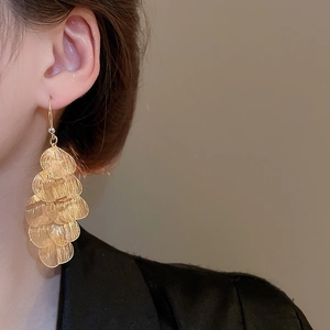 Close-up of elegant gold layered petal tassel earrings worn by a female model