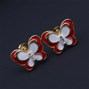 Macro shot of gold butterfly earrings with red and white enamel and zircon stones