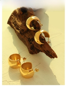 Detaillierte Nahaufnahme goldener klobiger C-Creolen mit hochglanzpolierter Spiegeloberfläche
