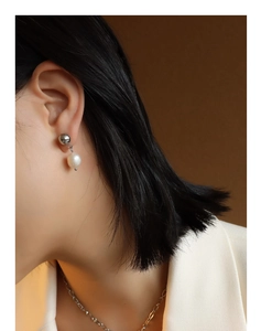 Detail of freshwater pearl earring on model with white blazer and minimalist metal ball stud