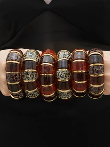 Chunky leopard resin bracelet set with gold-plated metal links on a model's wrist