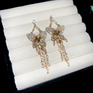 Detailed macro view of butterfly tassel earrings with sparkling crystals on a white display
