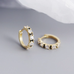 Macro shot of gold huggie earrings featuring clear and black cubic zirconia stones