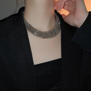Close-up of wide silver layered metal choker necklace on model in black suit