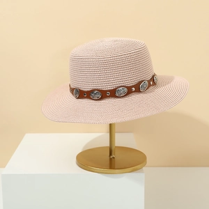 Detail of pink straw sun hat featuring a brown leather belt with silver studded buckles