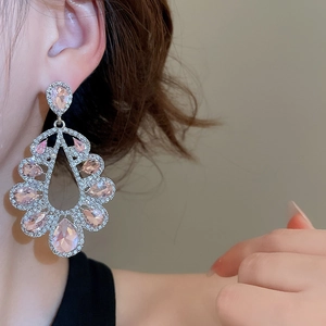 Detail of elegant hollow teardrop earrings featuring pink stones and white crystals