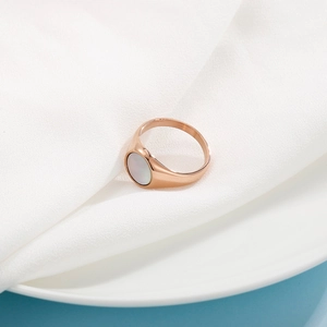 Detailed view of rose gold ring featuring a round mother of pearl inlay on white fabric
