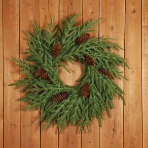 Artificial pine Christmas wreath with natural pinecones hanging on a rustic wooden door