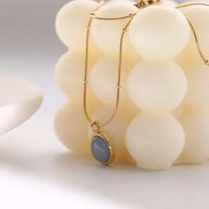 Golden necklace with circular grey natural stone pendant on white decorative spheres