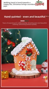 Detailed view of gingerbread house ornament with snow roof and festive wreath decorations