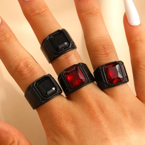 Details von vier klobigen Gothic-Ringen mit roten und schwarzen Steinen an der Hand