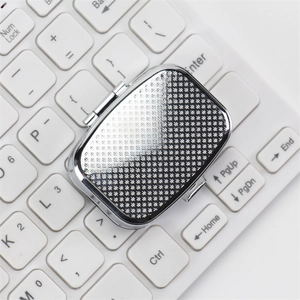 Portable silver square metal pill box with diamond lattice texture on laptop keyboard