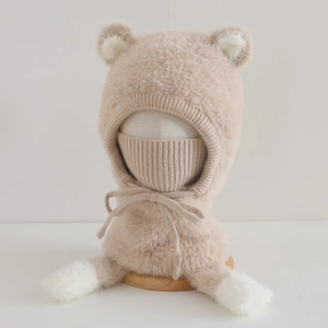 Detail of plush winter bear hat with integrated neck warmer and soft pom-poms in beige
