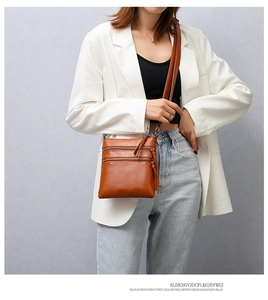 Brown leather crossbody phone bag featuring three tiered zipper pockets and long tassels
