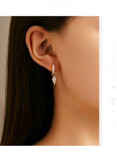 Close-up of s925 silver hoop earring with kite-shaped diamond pendant worn on ear