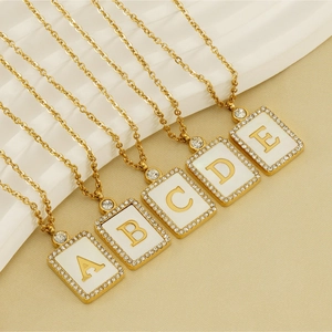 Detailed macro of gold square letter pendants with crystal borders and white enamel finish