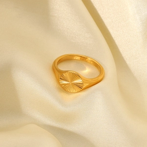 Détail de la bague en or 18K avec texture soleil sur fond de soie de couleur beige
