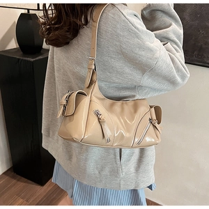 Detail of beige patent leather shoulder bag with silver zipper on a female model