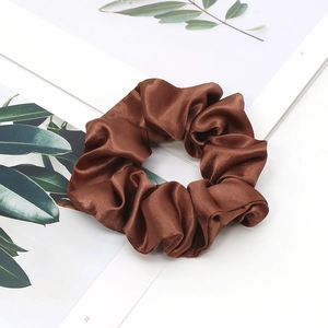 Close-up of shiny dark brown satin scrunchie on a decorative card for hair styling
