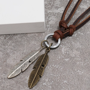 Macro shot of retro alloy feather pendants on brown braided leather necklace strap
