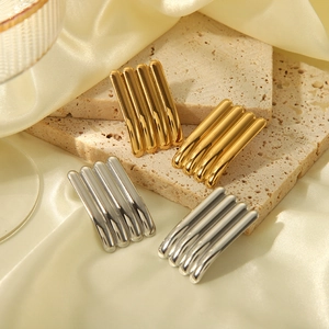 Detail von rechteckigen Ohrsteckern in Gold und Silber auf elegantem Seidenhintergrund