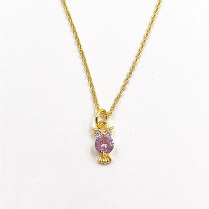 Detailed macro shot of an owl pendant with large pink zircon and gold-plated chain