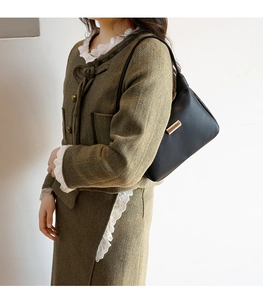 Close-up of black lychee grain leather underarm bag with gold metal hardware details