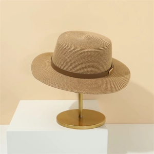 Retro khaki straw sun hat with wide brim and leather strap on a minimal display stand