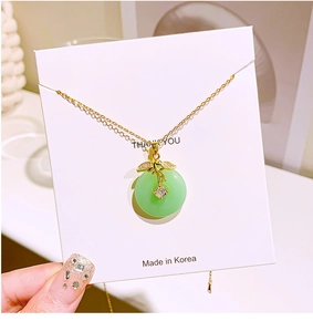 Detail of faux jade pendant with golden leaf and crystals on delicate steel chain