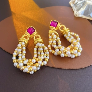 Detail of vintage earrings with ruby stone and elegant white pearl tassels on leather