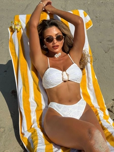 White textured bikini set with golden metal ring detail on beach background