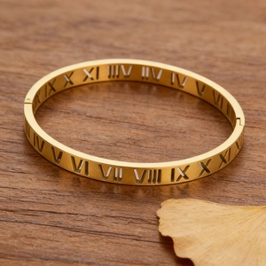 Gros plan d'un bracelet ajouré doré à chiffres romains sur bois avec feuille de ginkgo