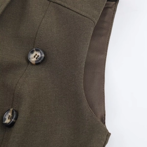 Detailed close-up of dark olive layered dress showing seam stitching and faux tortoiseshell button