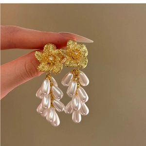 Close-up of elegant gold flower earrings with cascading white teardrop pearls