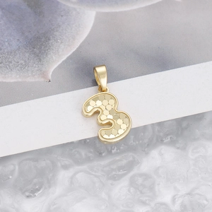 Detailed view of a gold number 3 pendant with honeycomb texture on a white surface