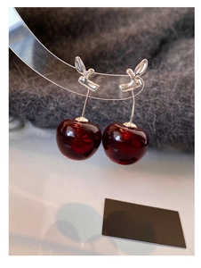 Macro shot of dark red resin cherry pendant earrings with silver metal stems detail