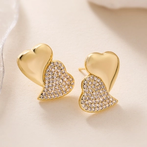 Macro shot of gold-plated double heart stud earrings with sparkling zircon crystals