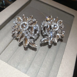 Macro shot of silver flower earrings with high-quality rhinestones on grey velvet tray