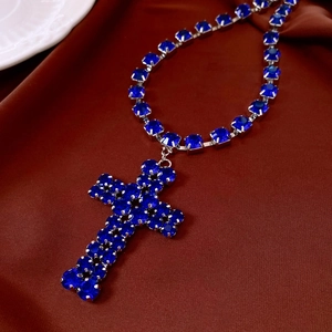 Macro detail of deep blue rhinestone cross pendant with silver plating and luxury square link chain