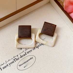 Detail of vintage geometric earrings with brown wood and creamy resin on a decorative tray