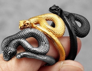 Detailed close-up of snake wrap rings in silver, gold, and black with scale texture