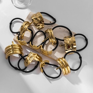 Detail showing gold metal cuffs with smooth and textured finishes on black hair ties