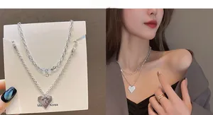 Close-up of double-layer silver necklace featuring heart pendant with bow relief