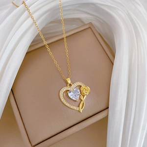 Close-up of golden heart pendant with center crystal and rose on jewelry box