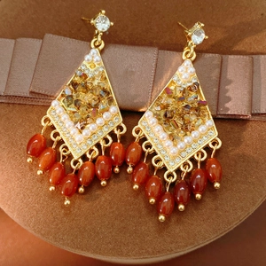 Primer plano de pendientes vintage en forma de rombo con piedras de vidrio y borlas
