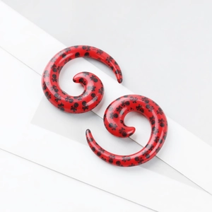 Détails macro des écarteurs d'oreilles spirales rouges avec motifs têtes de mort