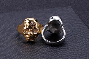 Macro view of gold and silver skull rings with rhinestone cross inlay detail on band