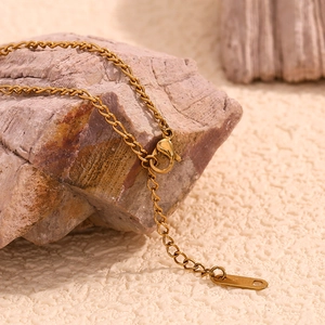 Macro detail of 18K gold plated Figaro chain with lobster clasp and K18 stamp on stone